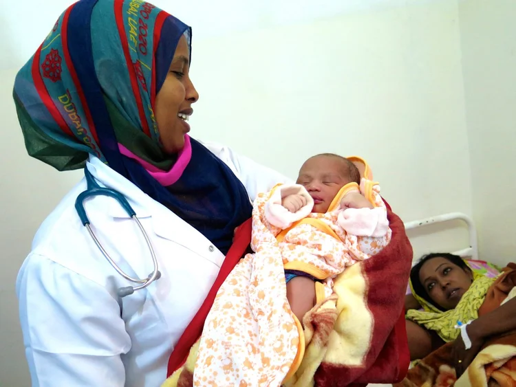 A doctor holding an infant patient