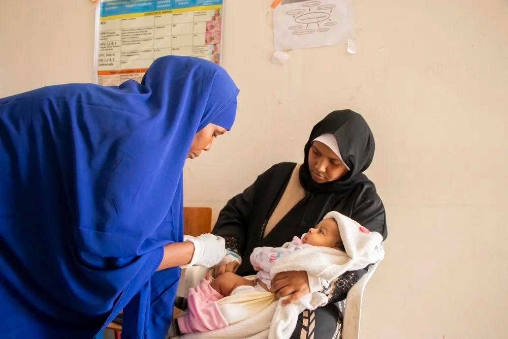 A nurse attending to a newborn baby while the mother looks on